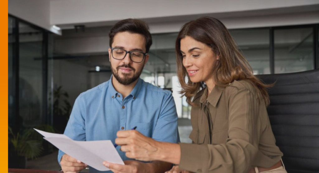 Two business professionals reviewing lease documents together in an office.