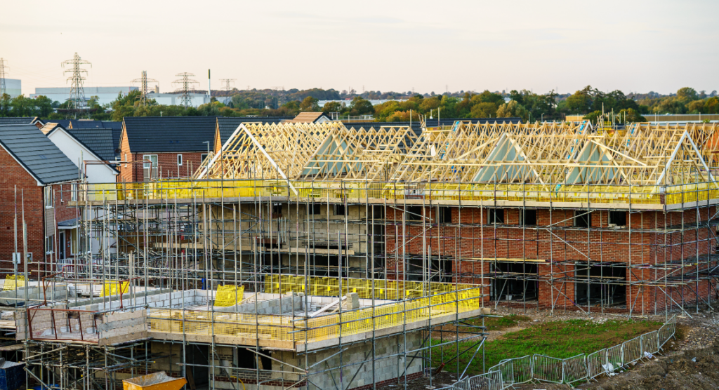 Residential property development under construction with scaffolding and timber roof structures.